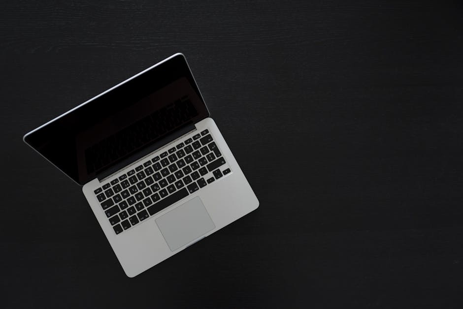 Overhead view of a MacBook laptop on a dark desk, showcasing modern technology and minimalism